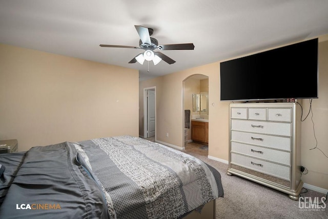 bedroom with light carpet, ensuite bathroom, a ceiling fan, arched walkways, and baseboards