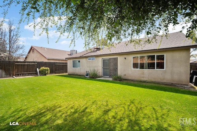 back of property with stucco siding, a lawn, and fence private yard