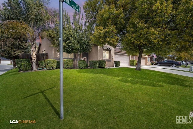 obstructed view of property featuring fence, driveway, an attached garage, stucco siding, and a front lawn