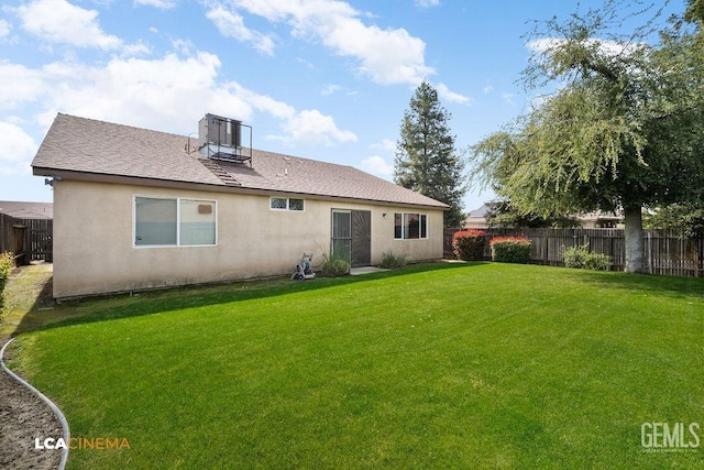 rear view of house featuring a yard, a fenced backyard, and stucco siding