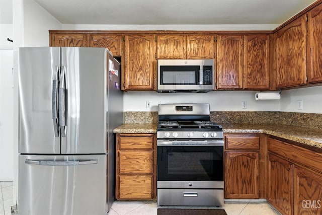 3023 Esperanza Dr, Bakersfield, CA 93313 - kitchen with stainless steel appliances, light tile patterned floors, and brown cabinets