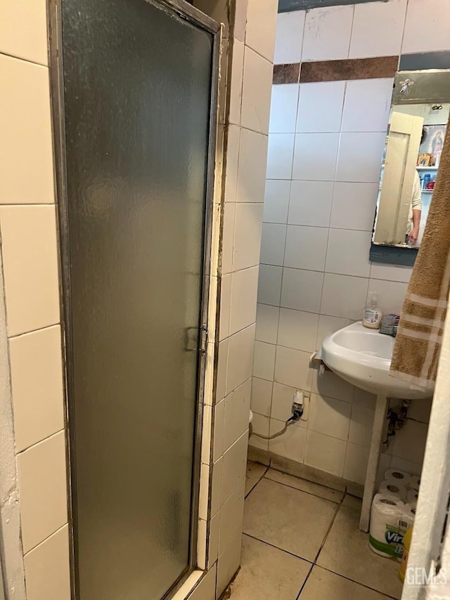 bathroom with tile patterned floors, a shower with door, and tile walls