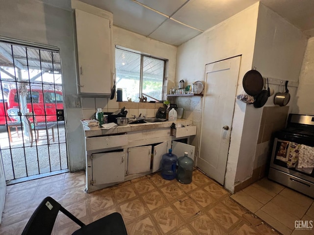 kitchen with white cabinetry, stainless steel range oven, sink, and tasteful backsplash