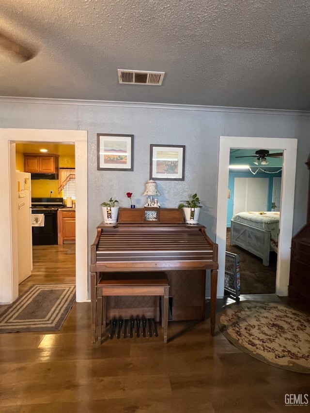 220 Tyler St, Taft, CA 93268 - detailed view of crown molding, wood finished floors, a textured ceiling, range, and ceiling fan