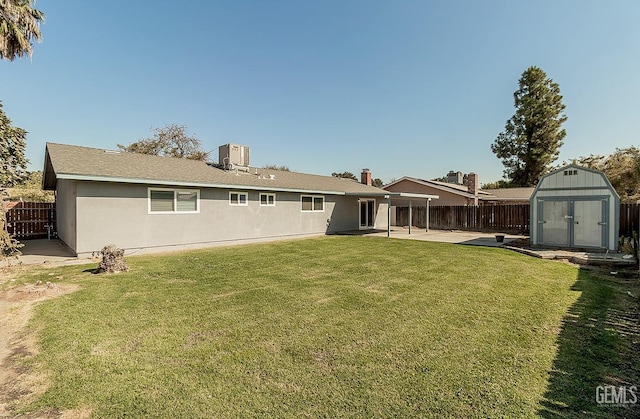 rear view of property featuring central air condition unit, a yard, a patio, and a storage unit