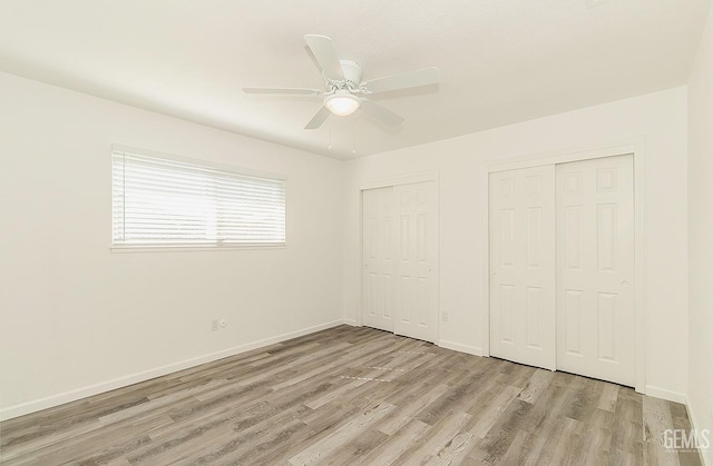 unfurnished bedroom with ceiling fan, light hardwood / wood-style floors, and two closets