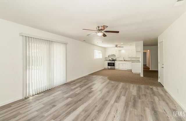 unfurnished living room featuring light hardwood / wood-style flooring, ceiling fan, and sink