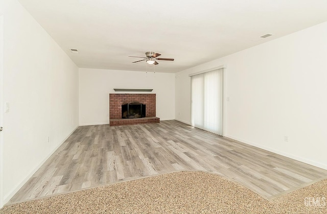 unfurnished living room featuring light wood-type flooring, a brick fireplace, and ceiling fan