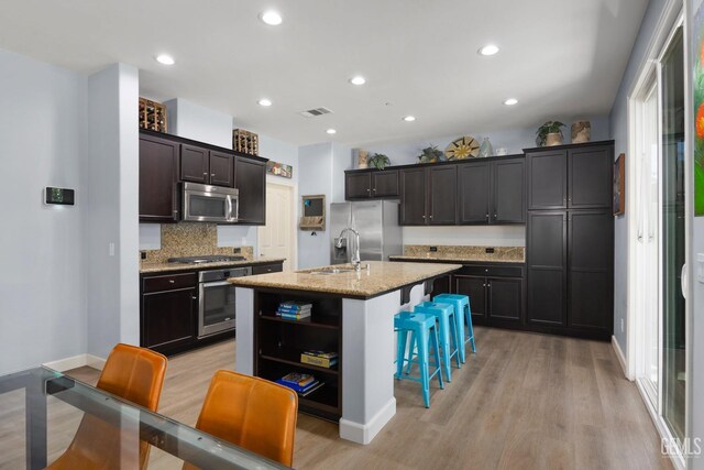 8113 Mcgraw Hill Dr, Bakersfield, CA 93311 - kitchen featuring light wood finished floors, a sink, a kitchen bar, decorative backsplash, and appliances with stainless steel finishes