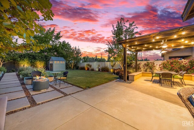 8113 Mcgraw Hill Dr, Bakersfield, CA 93311 - view of patio featuring a fenced backyard, outdoor dining space, a shed, an outbuilding, and an outdoor fire pit