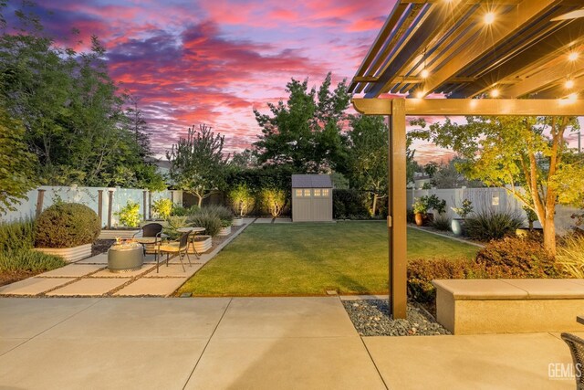 8113 Mcgraw Hill Dr, Bakersfield, CA 93311 - patio terrace at dusk featuring a fire pit, a lawn, a fenced backyard, and an outdoor structure