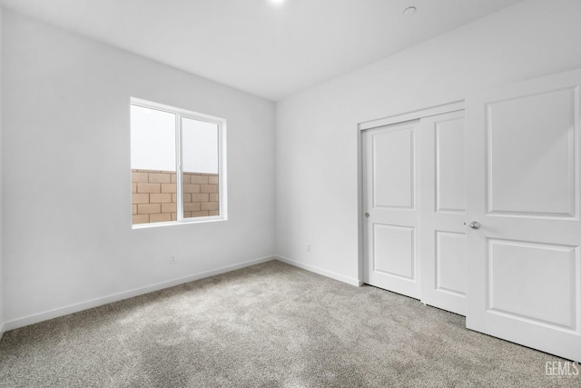 unfurnished bedroom with light colored carpet and a closet