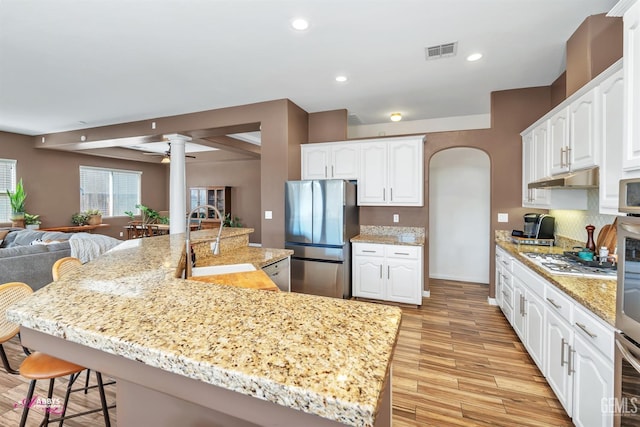 22 Emerald Isle Way, Bakersfield, CA 93314 - kitchen featuring a kitchen breakfast bar, visible vents, a sink, arched walkways, and appliances with stainless steel finishes