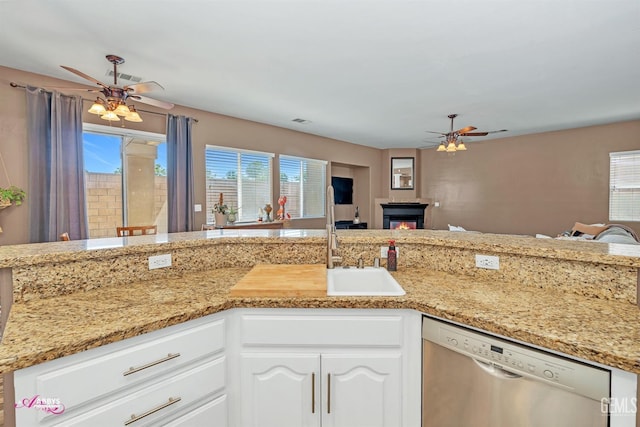 22 Emerald Isle Way, Bakersfield, CA 93314 - kitchen featuring ceiling fan, stainless steel dishwasher, a glass covered fireplace, and white cabinets