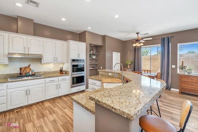 22 Emerald Isle Way, Bakersfield, CA 93314 - kitchen with light wood finished floors, a kitchen breakfast bar, a sink, visible vents, and stainless steel double oven