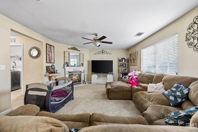 9301 Cobble Mountain Rd, Bakersfield, CA 93313 - living area with light carpet, a ceiling fan, a warm lit fireplace, baseboards, and washer / clothes dryer