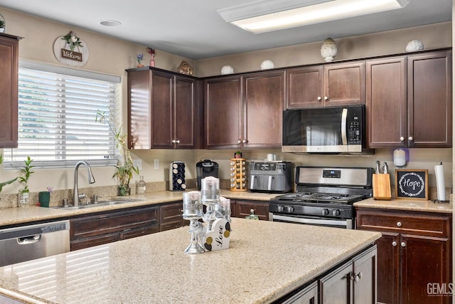 9301 Cobble Mountain Rd, Bakersfield, CA 93313 - kitchen with appliances with stainless steel finishes, a sink, dark brown cabinets, light stone countertops, and a kitchen island