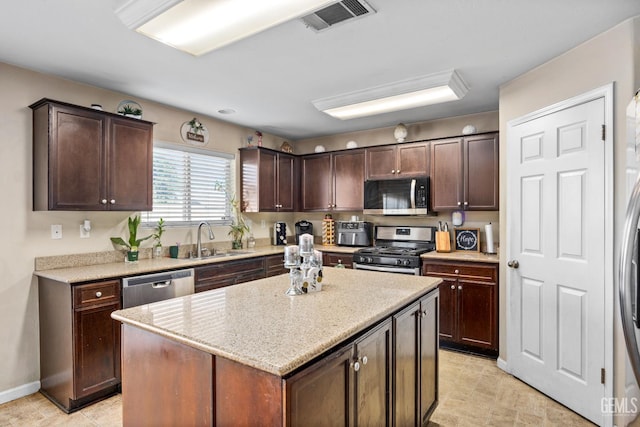 9301 Cobble Mountain Rd, Bakersfield, CA 93313 - kitchen with stainless steel appliances, a sink, dark brown cabinets, a kitchen island, and baseboards