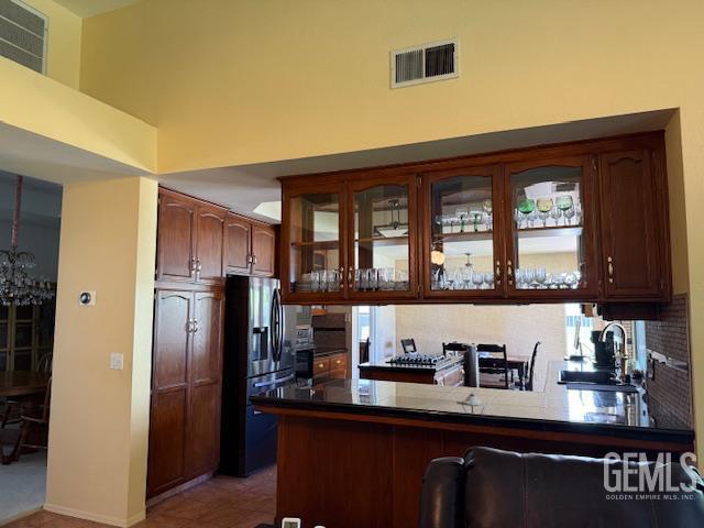 2012 Calle Las Brisas, Bakersfield, CA 93309 - kitchen featuring stainless steel fridge with ice dispenser, a peninsula, glass insert cabinets, dark countertops, and a chandelier