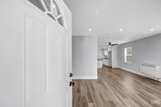 interior space with heating unit, light hardwood / wood-style flooring, and ceiling fan