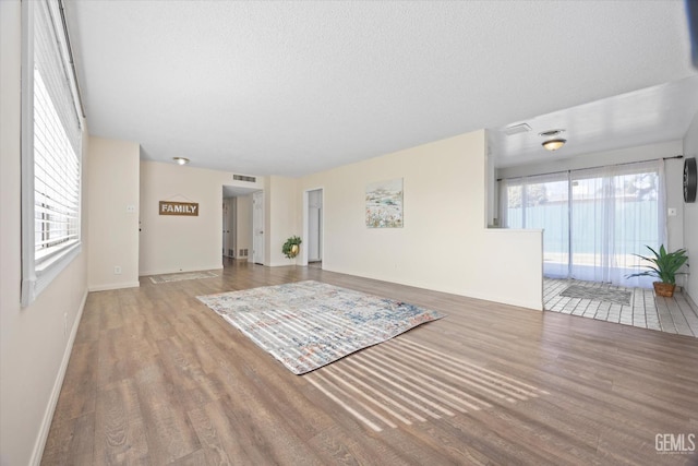 unfurnished room with plenty of natural light, a textured ceiling, and light wood-type flooring