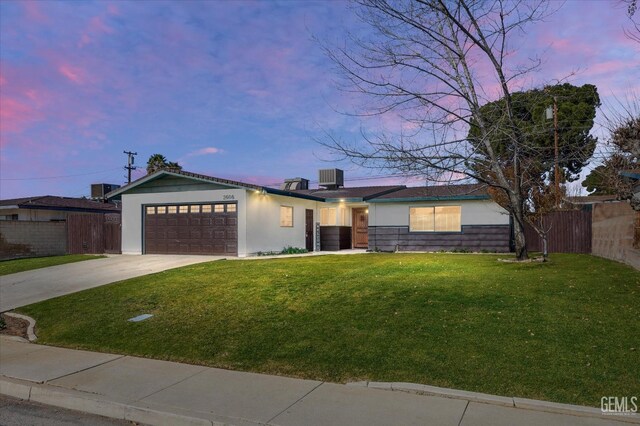 view of front of home featuring a garage, a yard, and central air condition unit