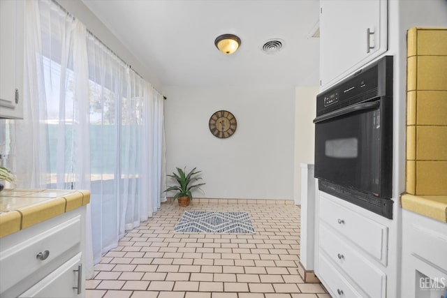 kitchen with tile countertops, oven, and white cabinets