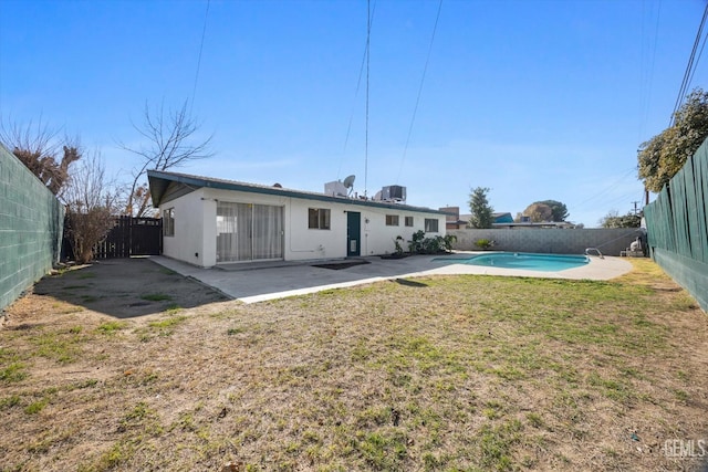 back of property with cooling unit, a fenced in pool, a patio area, and a lawn