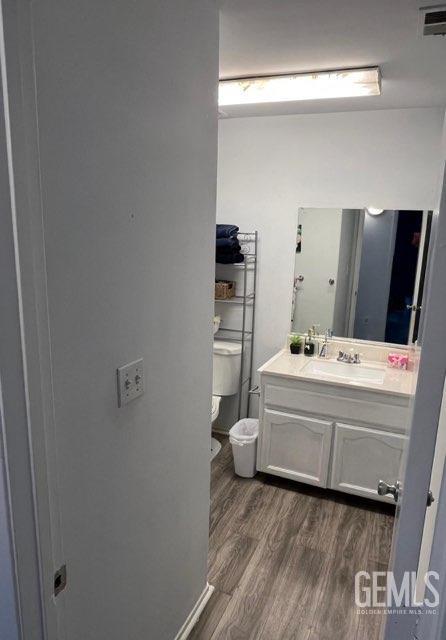 1024 Hazelnut St, Wasco, CA 93280 - bathroom featuring wood finished floors, toilet, and vanity