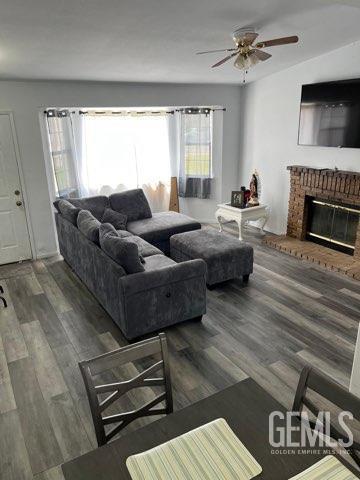 1024 Hazelnut St, Wasco, CA 93280 - living room featuring a ceiling fan, wood finished floors, and a brick fireplace
