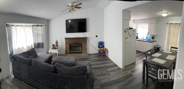 1024 Hazelnut St, Wasco, CA 93280 - living room with ceiling fan, dark wood-style floors, a fireplace, and lofted ceiling