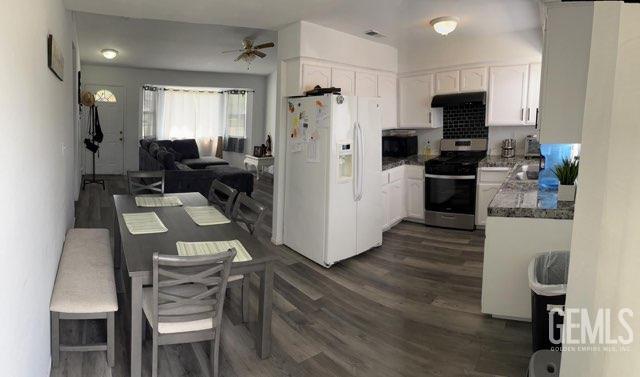 1024 Hazelnut St, Wasco, CA 93280 - kitchen with white refrigerator with ice dispenser, stainless steel range with gas cooktop, white cabinetry, dark wood-style flooring, and ceiling fan