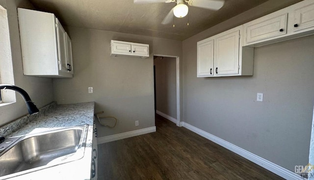 kitchen featuring light stone countertops, dark hardwood / wood-style flooring, ceiling fan, sink, and white cabinets