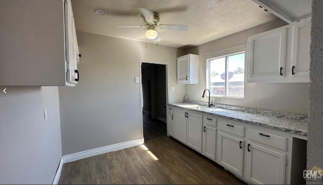 kitchen with white cabinets, sink, dark hardwood / wood-style floors, ceiling fan, and light stone countertops