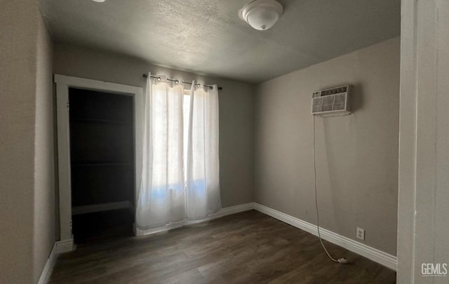 spare room with dark hardwood / wood-style floors and a wall unit AC