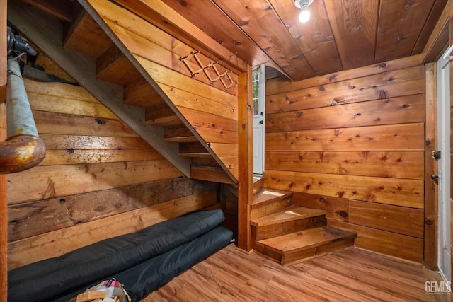 staircase with wooden ceiling, hardwood / wood-style flooring, and wooden walls