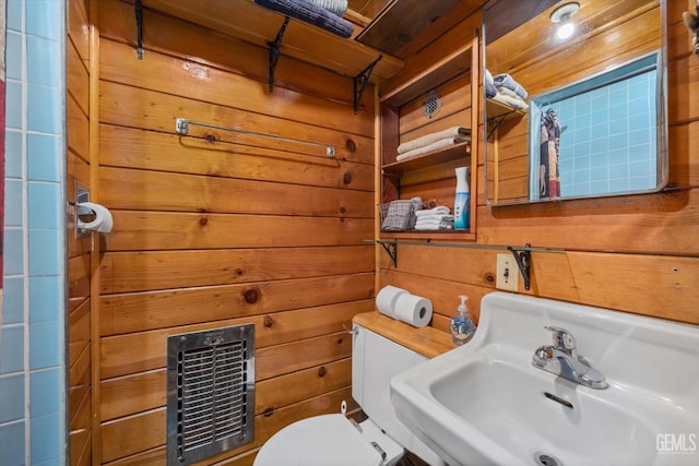 bathroom with wood walls, toilet, sink, and heating unit