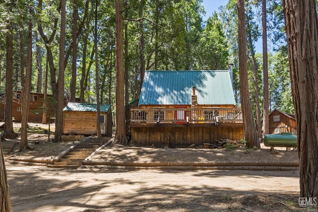 cabin featuring a wooden deck and a storage shed