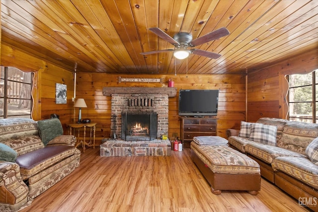 living room with ceiling fan, wooden ceiling, a brick fireplace, wood walls, and light hardwood / wood-style floors