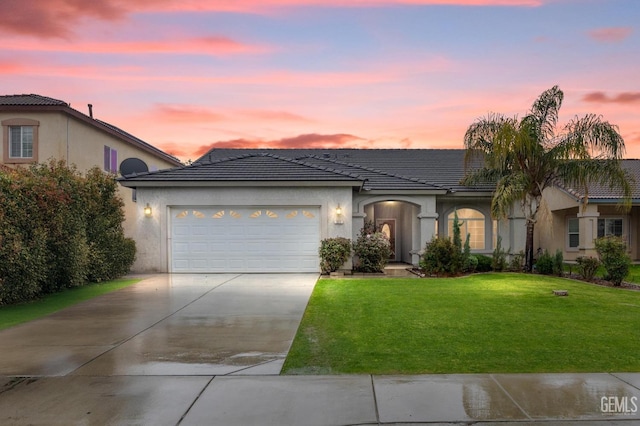 view of front of property with a garage, a yard, driveway, and stucco siding