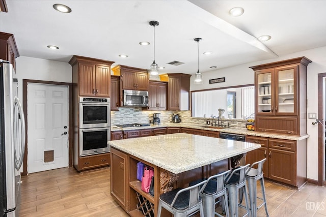 kitchen featuring sink, tasteful backsplash, decorative light fixtures, a kitchen island, and stainless steel appliances