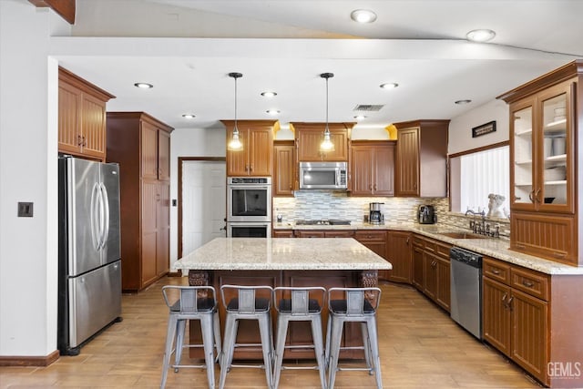 kitchen featuring appliances with stainless steel finishes, backsplash, decorative light fixtures, a center island, and a breakfast bar area