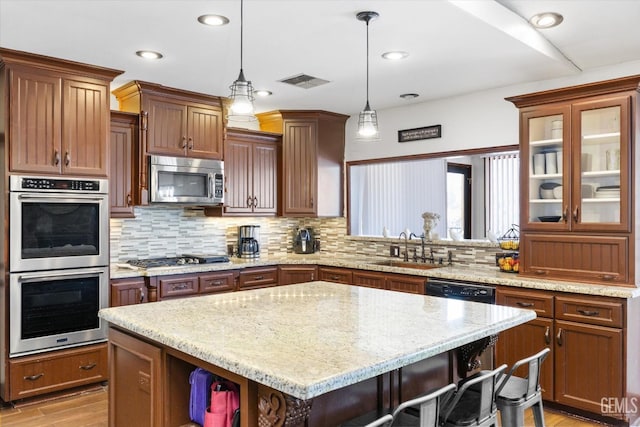 kitchen featuring sink, appliances with stainless steel finishes, tasteful backsplash, a kitchen island, and a breakfast bar area