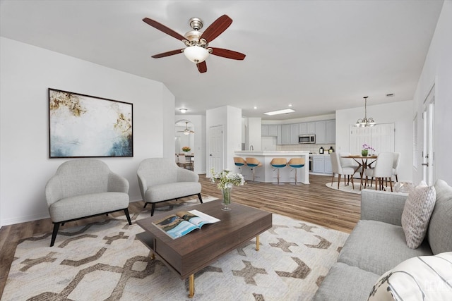 living room featuring baseboards, light wood-style floors, and ceiling fan