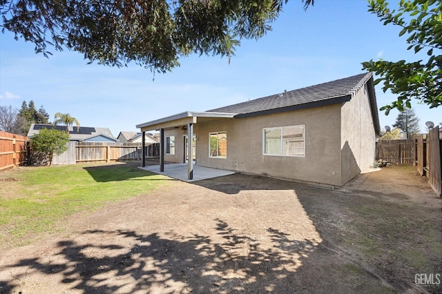 back of property with a fenced backyard, stucco siding, a lawn, and a patio