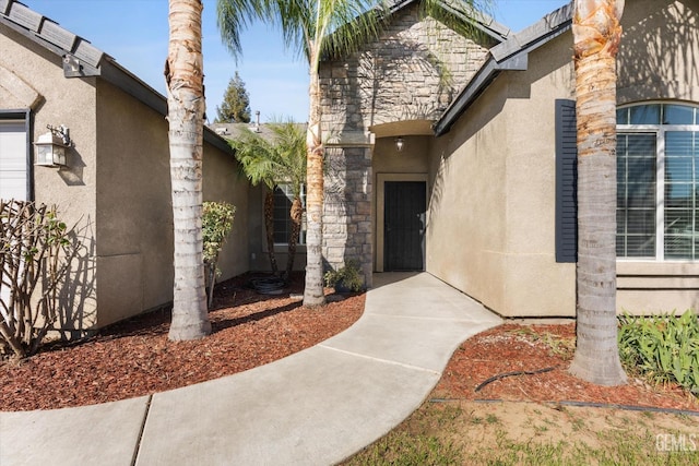 view of exterior entry featuring stone siding and stucco siding