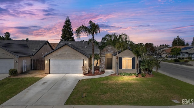 view of front facade with stucco siding, driveway, a tile roof, a front yard, and an attached garage