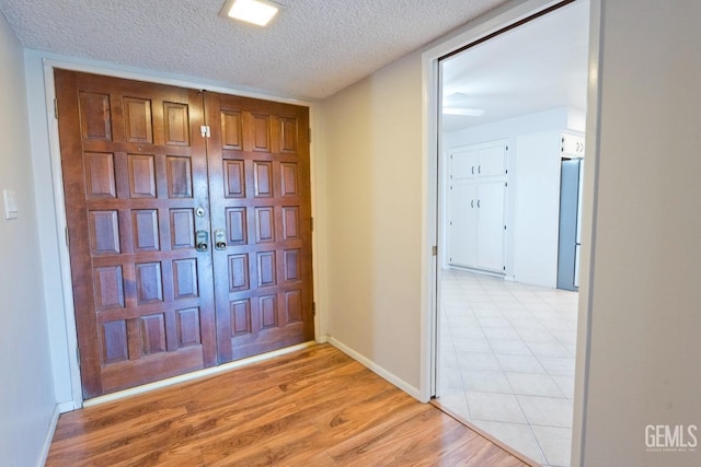 foyer entrance with a textured ceiling and light hardwood / wood-style floors