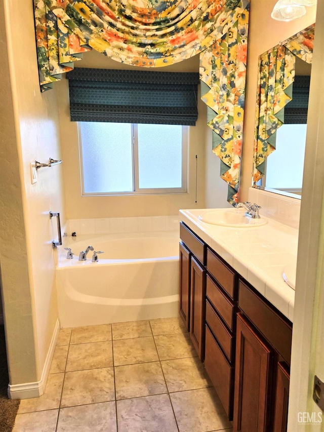 bathroom with double vanity, baseboards, a sink, tile patterned flooring, and a bath