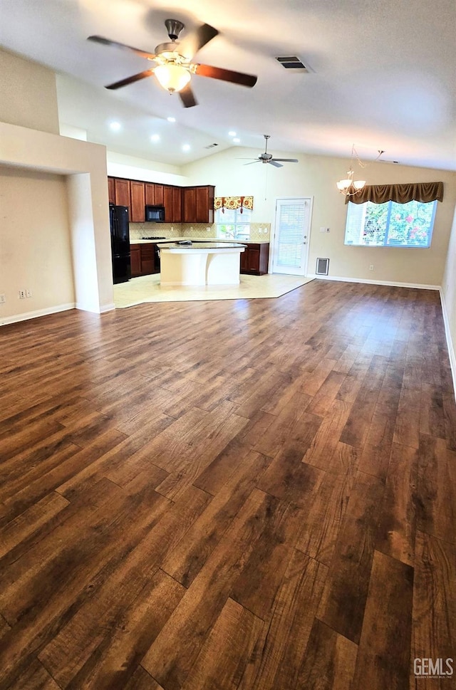 unfurnished living room with baseboards, visible vents, vaulted ceiling, and dark wood finished floors